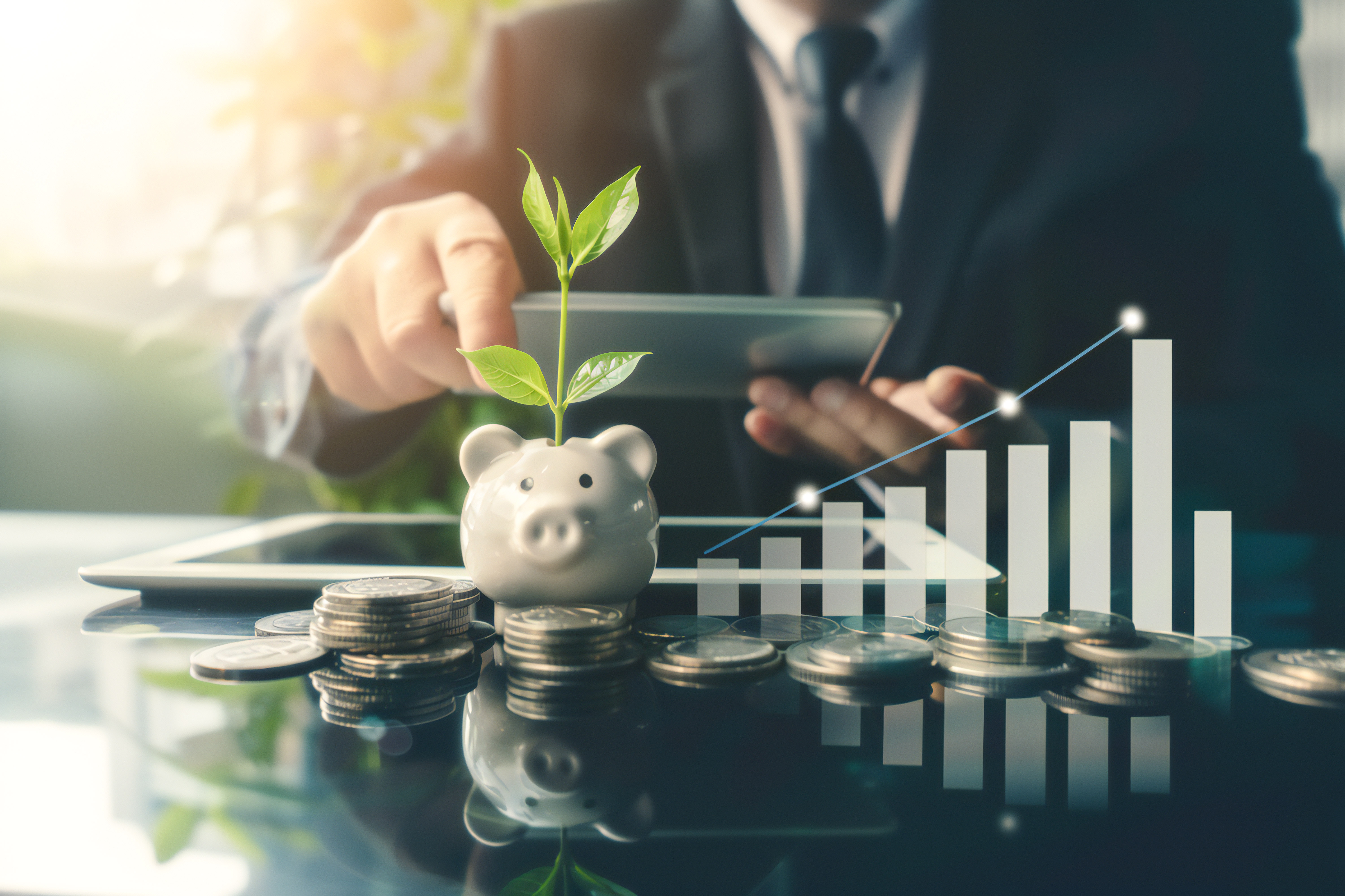 A business man looking over finances with a pile of coins and a piggy bank sit in the foreground